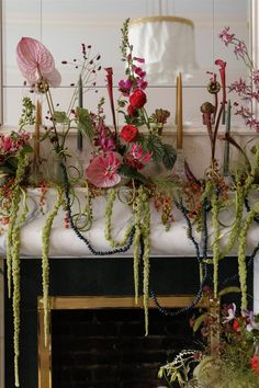 flowers and plants are arranged on the mantle