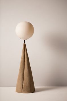 a white lamp sitting on top of a wooden table next to a brown cone shaped object