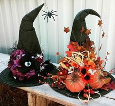 two witches hats sitting on top of a wooden table next to flowers and pumpkins