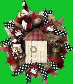 a christmas wreath with santa hats and other holiday decorations on it, against a green background