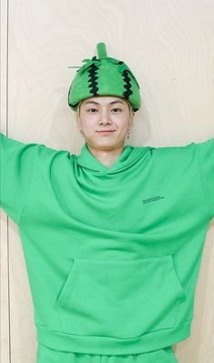 a young woman wearing a green outfit with a monster hat on top of her head