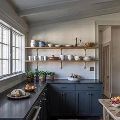 a kitchen filled with lots of counter top space and open shelving above the sink