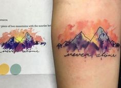 a watercolor tattoo with mountains and the words never give up on it's arm