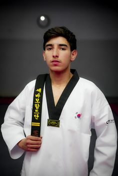 a young man wearing a black belt and white shirt