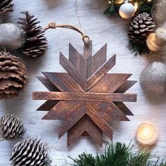 a wooden snowflake ornament surrounded by pine cones