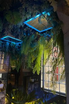 the interior of a building with plants growing on it's walls and lights hanging from the ceiling