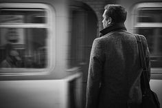 a man standing in front of a subway train looking out the window at another person