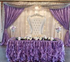 a chair and table covered in purple ruffled cloths with white flowers on it