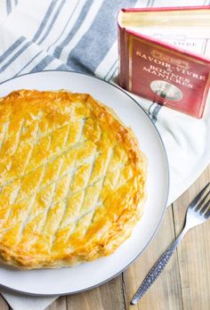 a pie on a plate next to a book and fork