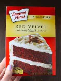 a red velvet cake with white frosting is being held up by someone's hand