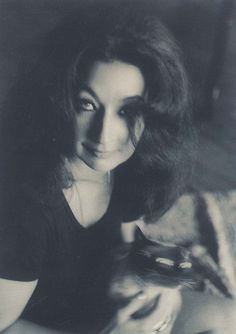 an old black and white photo of a woman with long hair holding a cell phone