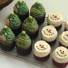 cupcakes decorated with frosting and christmas trees on a cooling rack, ready to be eaten