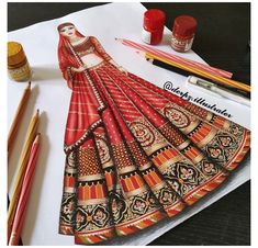 a drawing of a woman's dress on paper with markers and pencils next to it