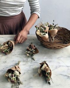 a woman is arranging flowers in baskets on a table with an arrow pointing to them