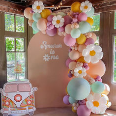 an arch made out of balloons and flowers is displayed in front of a vw bus