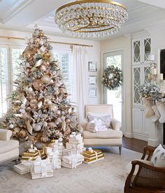 a decorated christmas tree in a living room with gold and silver ornaments on the top