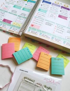 an open planner book sitting on top of a table next to a pile of sticky notes