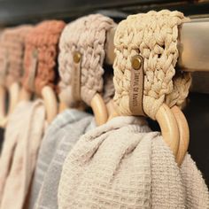 several knitted bags hanging on hooks in a row