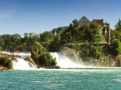 a castle on top of a waterfall in the middle of water with trees around it