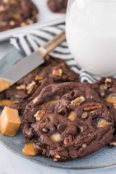 chocolate cookies with nuts and caramel are on a plate next to a glass of milk