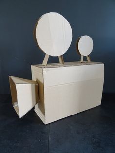 an open cardboard box with two mirrors on the top and one in the middle, sitting on a black floor