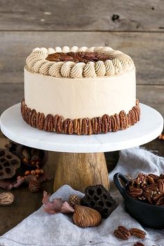 a white cake with pecans on top sitting on a table next to other desserts