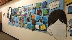 a bulletin board with pictures and words on it in an office hallway, next to a blue desk