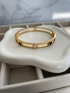 ✨Elevate your elegance with this stunning double-band gold bangle, a masterpiece of modern luxury. ✨Adorned with delicate quatrefoil motifs in glossy black and mother-of-pearl enamel, this piece is a celebration of contrast and refinement. ✨The open design creates a sense of lightness while still making a bold statement, ensuring every movement catches the eye. ✨Perfect for layering or wearing solo, this bangle is your new go-to for a chic yet daring look. ✨A sophisticated accessory that effortl Elegant Black Enamel Bangle For Gift, Elegant Black Enamel Bangle Bracelet, Elegant Black Enamel Bangle Gift, Luxury Gold Bangle With Black Enamel, Elegant Black Enamel Bangle, Gold Bangle, Open Design, Gold Bangles, Gold Bands