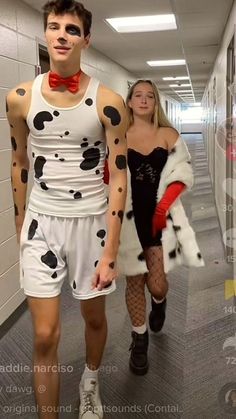 a man and woman in costumes walking down a hall way with dalmatian markings on their body