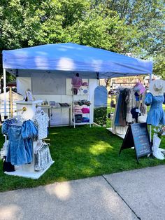 an outdoor tent with clothes on display in the grass