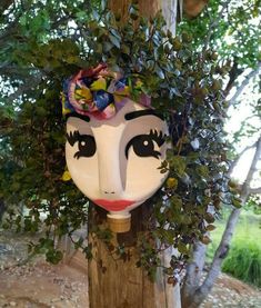 a white mask with flowers on it hanging from a tree