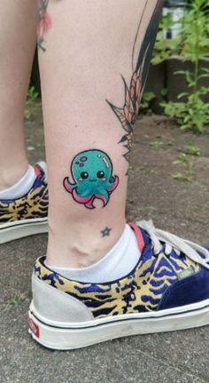 an octopus tattoo on the leg of a woman's foot, which is decorated with gold and blue designs