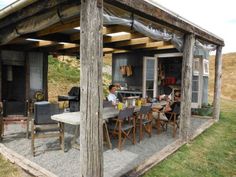 a group of people sitting at a table under a covered outdoor dining area in the grass