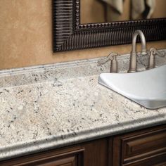 a bathroom sink sitting under a mirror next to a counter top with two faucets