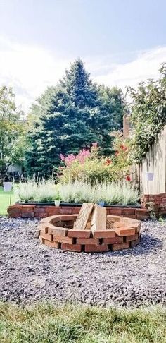 an outdoor fire pit in the middle of a graveled area with trees and bushes