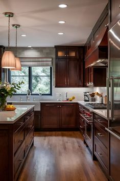 a large kitchen with wooden cabinets and stainless steel appliances, along with hardwood flooring