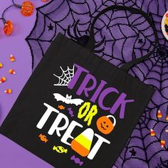 a trick or treat bag sitting on top of a purple surface with candy and candies