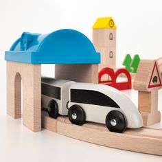 a wooden toy train set with cars and buildings