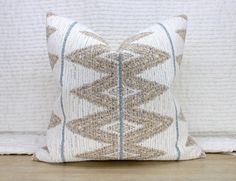 a white and blue pillow sitting on top of a wooden floor next to a wall