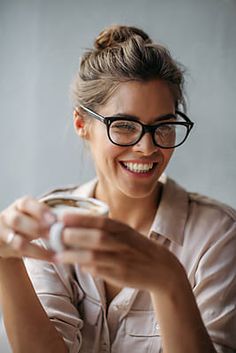 a woman in glasses is smiling and holding something up to her face by jovan for stocks