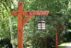 a wooden cross hanging from the side of a road next to a forest filled with trees