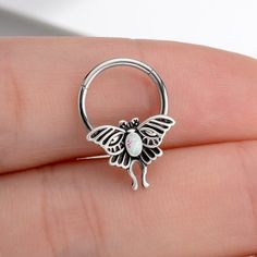 a person is holding a butterfly shaped nose ring