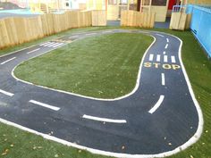 an artificial play area with a stop sign painted on the road and grass in front