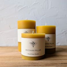 three beeswax pillar candles sitting on a table