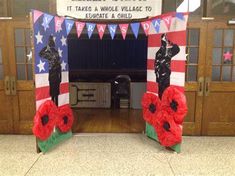 two red poppies are placed in front of an american flag decorated entrance to a school