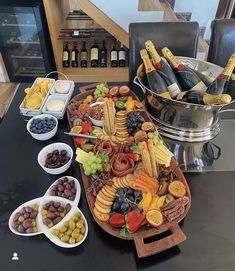 a large platter filled with lots of different types of food and wine bottles in the background