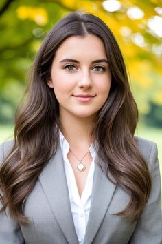 a woman with long hair wearing a gray suit and white shirt is smiling at the camera