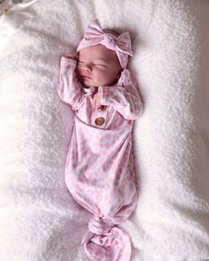 a baby is sleeping on a blanket with a pink bow around its head and it's eyes closed