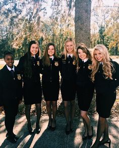 a group of young women standing next to each other in front of a tree with medals on their collars