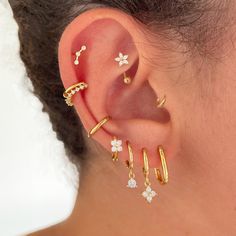 a woman wearing three different types of ear piercings